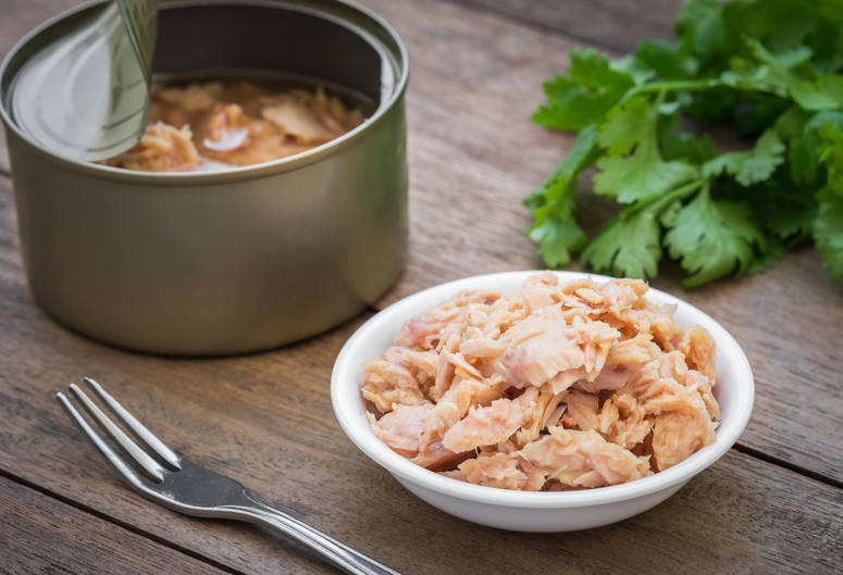 Atun en lata y sobre recipiente de vidrio Al lado de un tenedor
