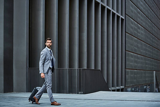 confident businessman with bag against building - hombres seguros fotografías e imágenes de stock